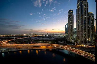 a city at night with a bridge and buildings at Seraya Residences at Urban Oasis by Missoni in Dubai