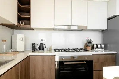 a kitchen with white cabinets and a stove top oven at Seraya Residence 11 - 3BDR - Private Jacuzzi and Infrared Sauna in Dubai