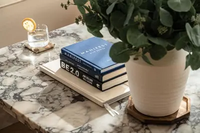 a table with books and a potted plant and a vase at Seraya Residence 12 - 3BDR - Hot Tub on patio with Burj view in Dubai