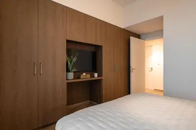a bedroom with a bed and a tv and wooden cabinets at Seraya Residence 12 - 3BDR - Hot Tub on patio with Burj view in Dubai