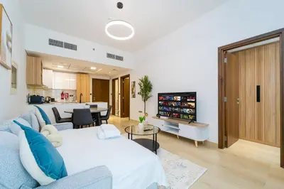 a living room with a blue couch and a tv at New Contemporary Lux and Pool & Kids Amenities in JVC in Dubai