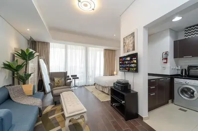 a living room with a blue couch and a bed at Luxury Living in Matrix Tower Near Sports City in Dubai
