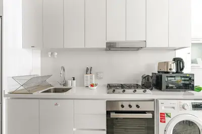 a white kitchen with a stove and a sink at Business Bay Studio Near Dubai Mall, Burj Khalifa & Downtown Hotspots in Dubai