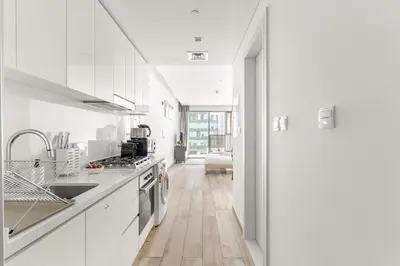a kitchen with white cabinets and a wooden floor at Business Bay Studio Near Dubai Mall, Burj Khalifa & Downtown Hotspots in Dubai