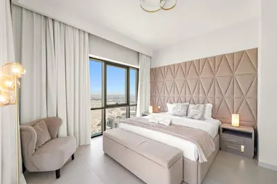 a bedroom with a large bed and a chair at FIRST CLASS 2BR Sun, Views & Serenity in Dubai