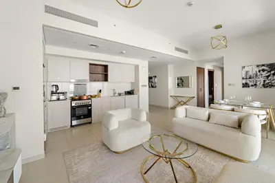 a living room with a couch and chairs and a kitchen at FIRST CLASS 2BR Sun, Views & Serenity in Dubai