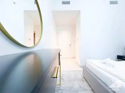 a white bedroom with a mirror and a bed at Luxurious 2BR in Burj Crown with Burj Khalifa View in Dubai