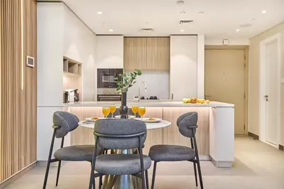 a kitchen with a table and chairs in a kitchen at Designer Apartments in Kensington Waters, MBR City, with Pool Gym Sauna & Parking near Downtown and Creek in Dubai