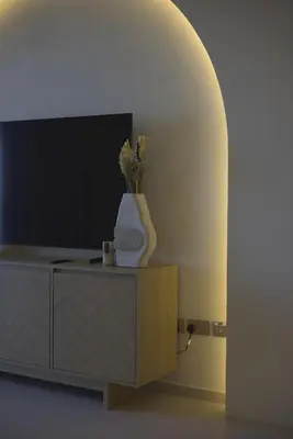 a living room with a tv and a vase on a cabinet at Top floor Grande 2BR Luxe Panoramic Sea View BohemianStyle in Dubai