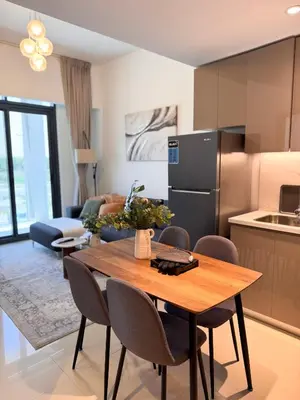 a kitchen and living room with a wooden table and chairs at COZY 1 BR Apartment in Dubai