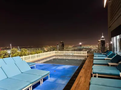 a rooftop pool with chaise lounge chairs at night at 2BR Burj Khalifa and Sea View Apartments in Paramount Hotel Midtown in Dubai