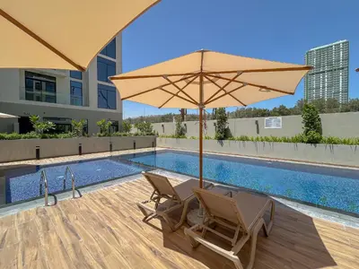 a patio with two chairs and an umbrella next to a pool at Luxurious Serenity 5-Star Lifestyle in JVC in Dubai
