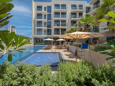 a swimming pool with an umbrella and a building at Luxurious Serenity 5-Star Lifestyle in JVC in Dubai