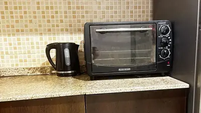 a black toaster oven sitting on a kitchen counter at Tranquil & Elegant Studio in Dubai Sports City in Dubai