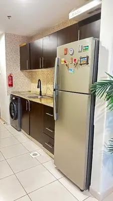 a kitchen with a stainless steel refrigerator and a sink at Tranquil & Elegant Studio in Dubai Sports City in Dubai