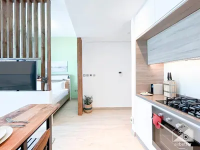 a kitchen with white walls and a wooden counter top at Balcony Bliss Cozy Studio with Marina Views in Dubai