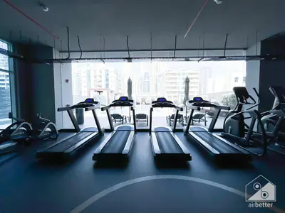 a gym with rows of treadmills and a large window at Balcony Bliss Cozy Studio with Marina Views in Dubai