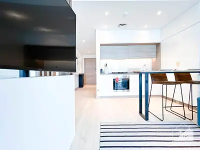 a kitchen with a blue table and a kitchen with white cabinets at Chic New Studio at Studio One Marina in Dubai