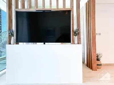 a flat screen tv on a white stand in a living room at New! Cozy & Stylish Studio at Studio One Marina in Dubai
