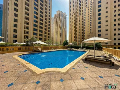 a swimming pool with an umbrella and benches and buildings at Boho Studio Beachfront Ain Sea View JBR Walk 1min in Dubai