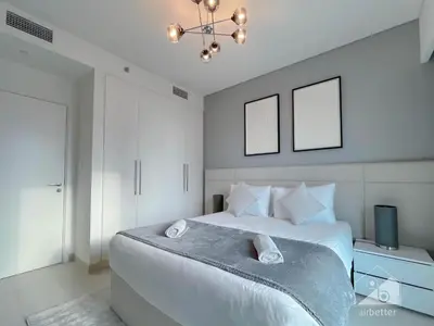 a bedroom with a large white bed and a chandelier at Burj Crown Luxury 2BR I Balcony & Panoramic Views in Dubai