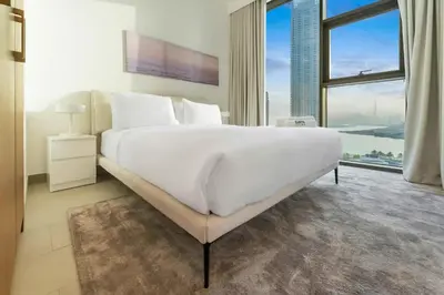 a large white bed in a room with a large window at FAM Living - 3BR Creekside Escape in Creek Rise Tower 2 in Dubai