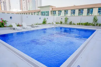 a large swimming pool with two white chairs on a building at Stylish Studio at Concord Concept, JVC in Dubai