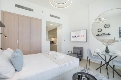 a white bedroom with a white bed and a table at Chic and comfortable Studio Near Downtown and Canal in Dubai