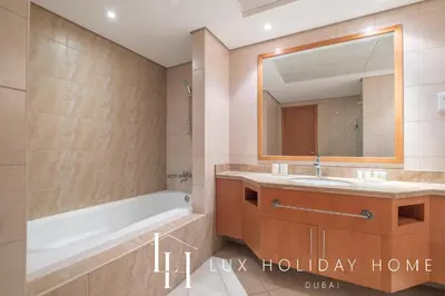 a bathroom with a tub and a sink and a mirror at LUX The Luxury Sunny JBR Beach Views 2 in Dubai