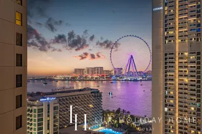 a view of a city with a ferris wheel at dusk at LUX The Luxury Sunny JBR Beach Views 2 in Dubai