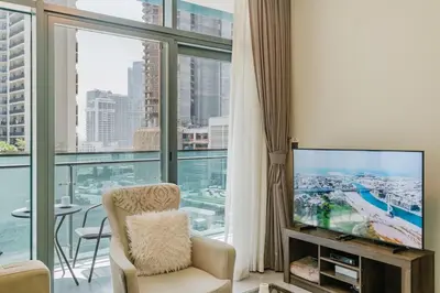 a living room with a tv and a large window at RH- Elegant & Cozy 1BR , Prime Location , Walk to Metro Station in Dubai