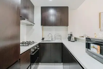 a kitchen with white counters and brown cabinets at RH- Elegant & Cozy 1BR , Prime Location , Walk to Metro Station in Dubai