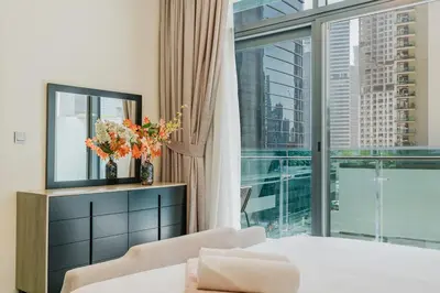 a bedroom with a bed and a large window at RH- Elegant & Cozy 1BR , Prime Location , Walk to Metro Station in Dubai