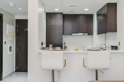 a kitchen with white counter tops and brown cabinets at RH- Elegant & Cozy 1BR , Prime Location , Walk to Metro Station in Dubai
