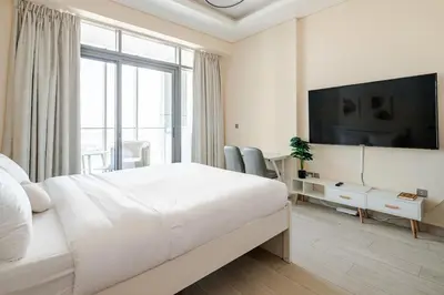 a white bedroom with a large bed and a flat screen tv at Cosy studio Free Parking Free unlimited drinkable water Near Downtown in Dubai