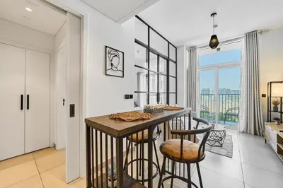 a kitchen with a table and two stools at Chic 1BR in Socio Dubai Hills Near Park and Mall in Dubai