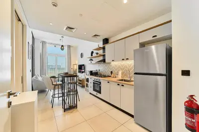 a kitchen with a stainless steel refrigerator and a table at Chic 1BR in Socio Dubai Hills Near Park and Mall in Dubai