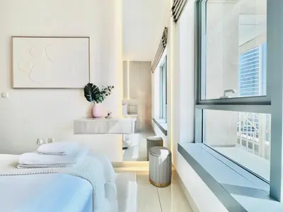 a white room with a bed and a sink at Venduras- Chic 1BR Getaway near Burj Khalifa in Dubai