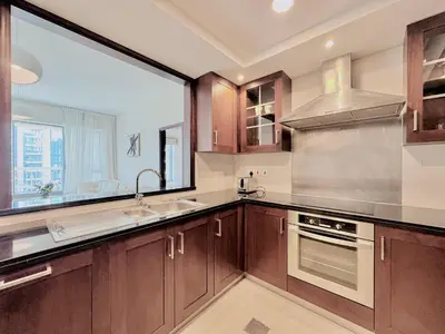 a kitchen with wooden cabinets and a large window at Venduras- Chic 1BR Getaway near Burj Khalifa in Dubai