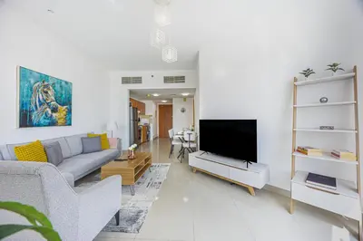 a living room with a couch and a flat screen tv at Chic 1BR Retreat with Lake Views & Modern Comforts in Dubai