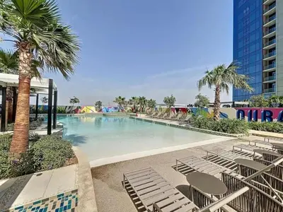 a large swimming pool with chairs and palm trees at Samani vacation homes 3108 canal view in Dubai
