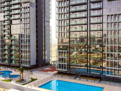 a view of two tall buildings and a swimming pool at Spacious JVC Studio Luxury Escape in Dubai