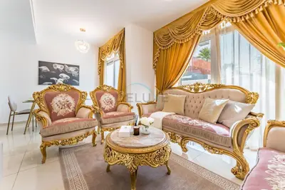 a living room with gold furniture and a table at Community and Pool View 3BR Townhouse, Minutes from Desert Camp,DAMAC Hills 2 Amargo by Deluxe Holiday Homes in Dubai