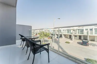 a balcony with two chairs and a table on a building at Community and Pool View 3BR Townhouse, Minutes from Desert Camp,DAMAC Hills 2 Amargo by Deluxe Holiday Homes in Dubai