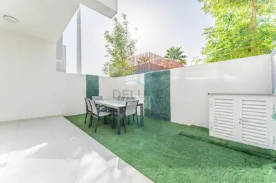 a dining room with a table and green grass at Community and Pool View 3BR Townhouse, Minutes from Desert Camp,DAMAC Hills 2 Amargo by Deluxe Holiday Homes in Dubai