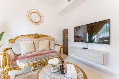 a bedroom with a gold bed and a tv at Community and Pool View 3BR Townhouse, Minutes from Desert Camp,DAMAC Hills 2 Amargo by Deluxe Holiday Homes in Dubai