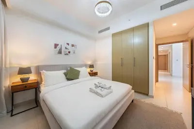 a bedroom with a large white bed and a table at Downtown Dubai 3BR Burj Royale in Dubai