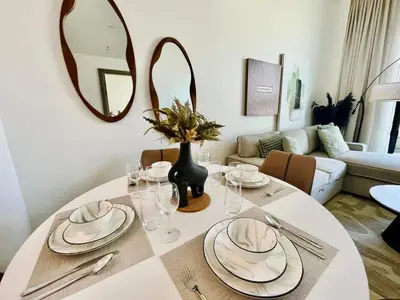 a dining room table with a white table cloth and a mirror at Comfortable 1br In Jvc Balcony Free Parking in Dubai