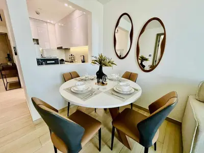 a dining room with a white table with chairs and mirrors at Comfortable 1br In Jvc Balcony Free Parking in Dubai
