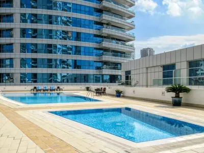 a swimming pool in front of a tall building at The Smart Concierge - Dorra Bay in Dubai